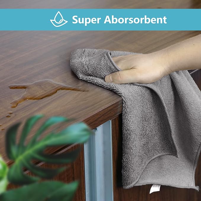 Gray towel being used to clean a wooden surface with 'Super Absorbent' text above.